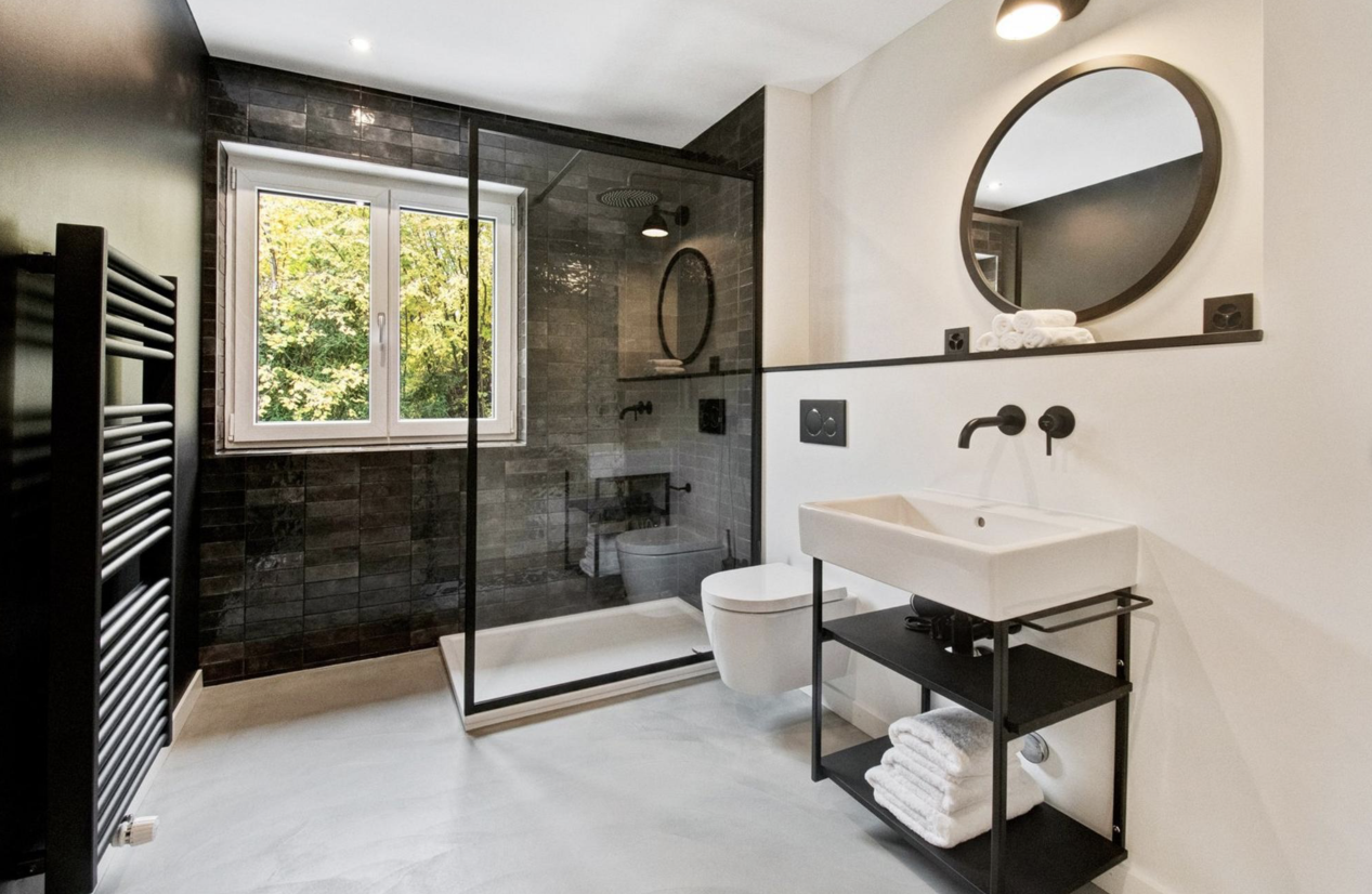 Badsanierung mit Tageslicht – moderne Ausstattung mit dunklen Fliesen, Walk-In-Dusche und Kontrastarmaturen Badsanierung mit Tageslicht – moderne Ausstattung mit dunklen Fliesen, Walk-In-Dusche und Kontrastarmaturen
