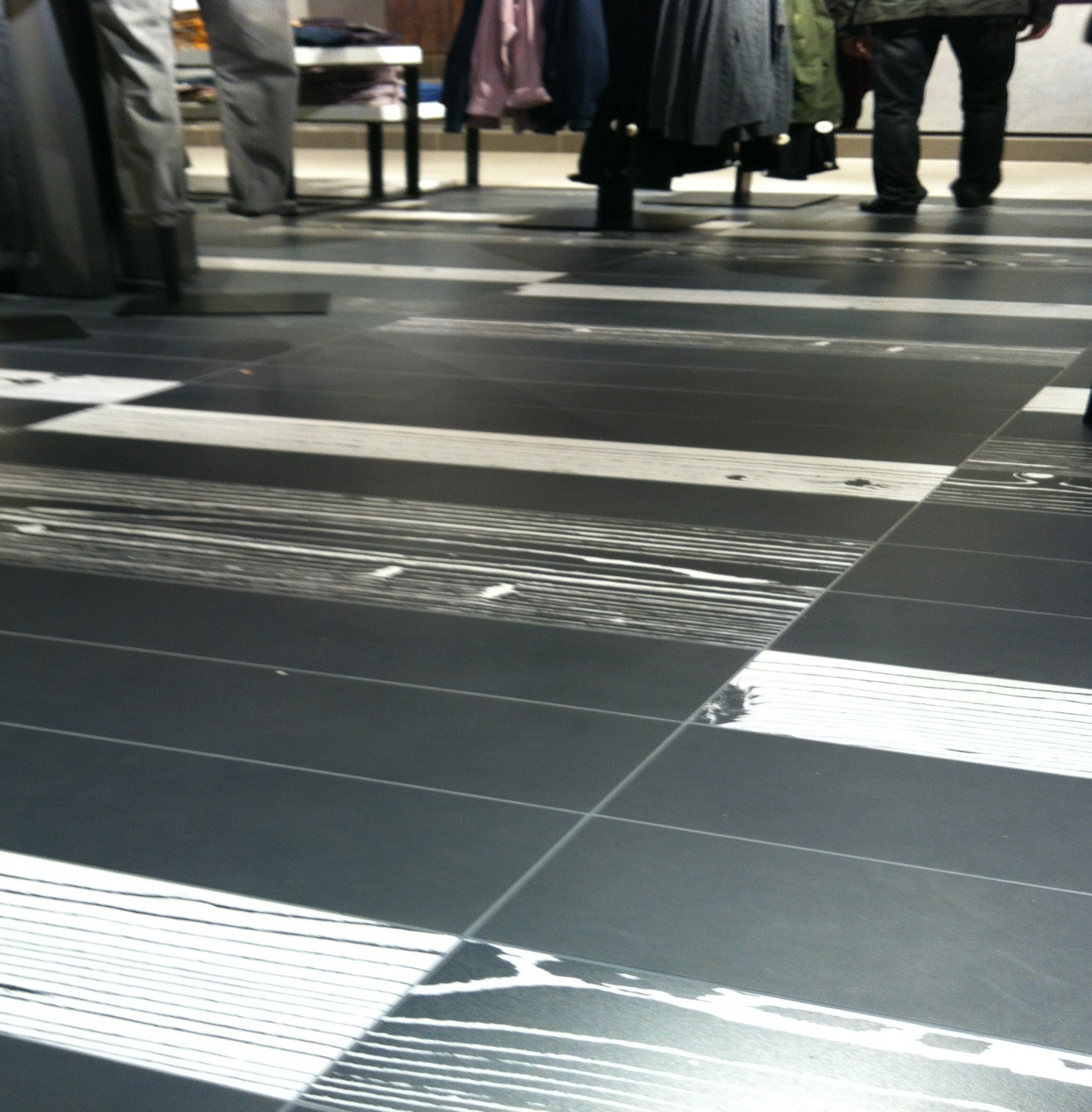 Verlegung grossformatiger Platten mit Schwarz-Weiß-Muster mit Parkettoptik – Innenausbau mit Designboden bei Manor Rapperswil Verlegung grossformatiger Platten mit Schwarz-Weiß-Muster mit Parkettoptik – Innenausbau mit Designboden bei Manor Rapperswil